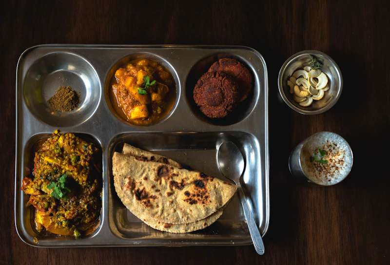 A steel thali with dal, sabzi, rice and roti